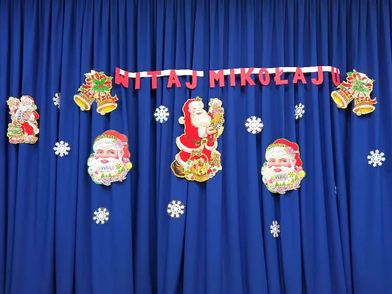Dekoracja: napis „Witaj Mikołaju!” otoczony ozdobami tj. świąteczne dzwonki, wizerunki Mikołajów, śnieżynki