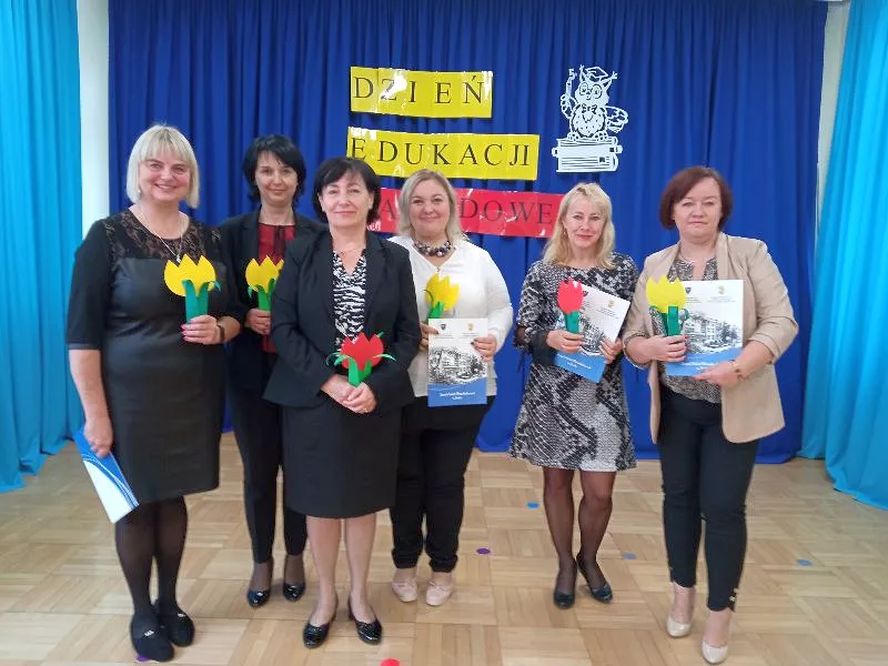 Panie Dyrektor i Wicedyrektor wraz z nagrodzonymi nauczycielkami stojące na tle dekoracji z papierowymi kwiatami
