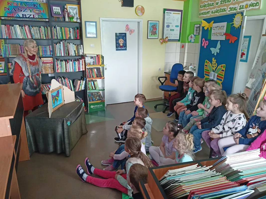 Pani bibliotekarka Gosia wita dzieci z przedszkola na zajęciach bibliotecznych.