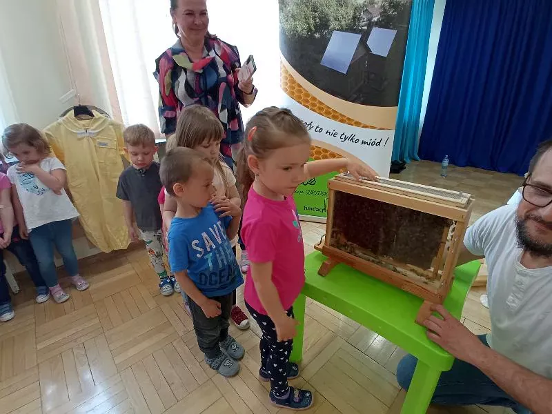 Dzieci po kolei przyglądają się pracy pszczół