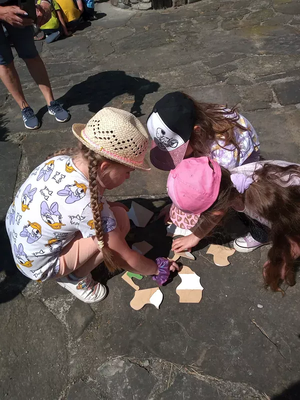 Dzieci w małych grupach wykonują kolejne zadanie – układają drewniane puzzle, na których są cyfry umożliwiające otwarcie drewnianej szkatułki z literami, z których na końcu powstanie imię smoka