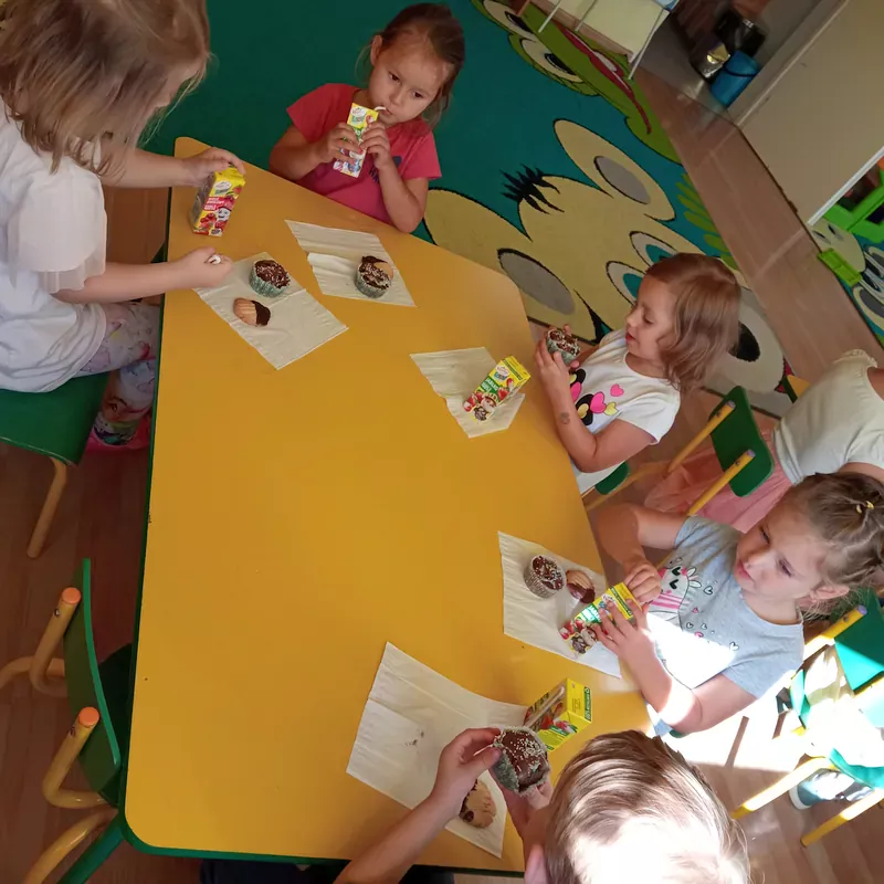 Dzieci siedzące przy stole podczas poczęstunku