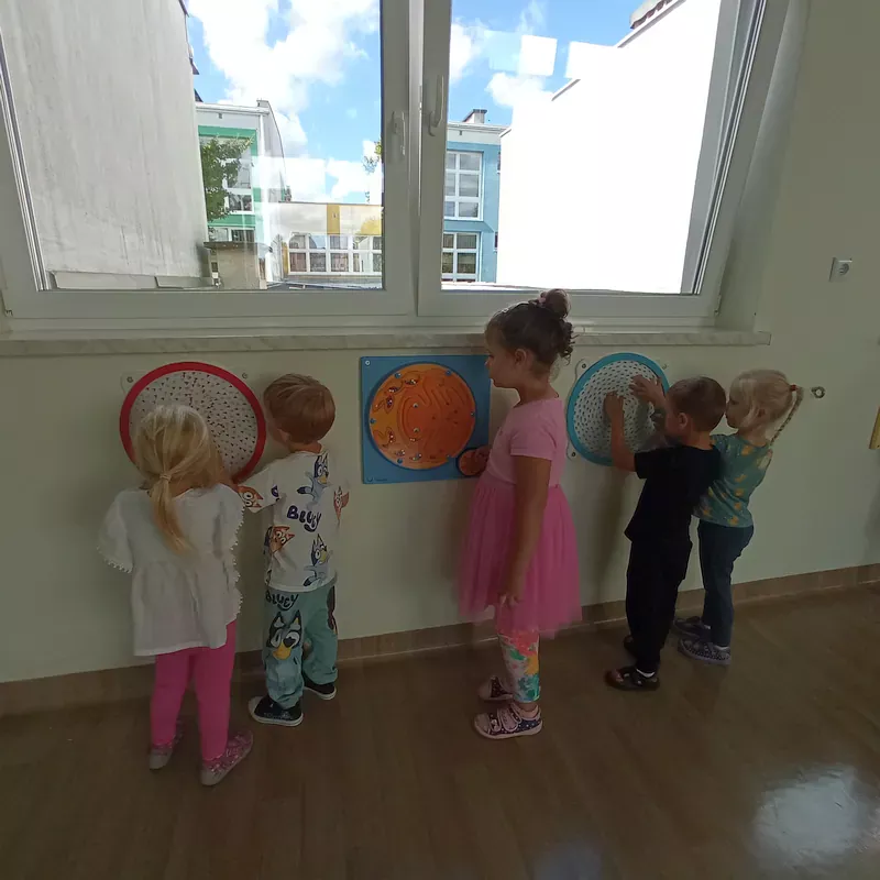 Dzieci podczas zabaw manipulacyjnych przy ściance sensoryczne w budynku B