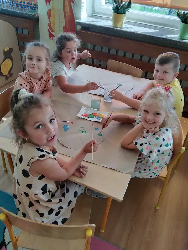Przedszkolaki przy stoliku podczas malowania.