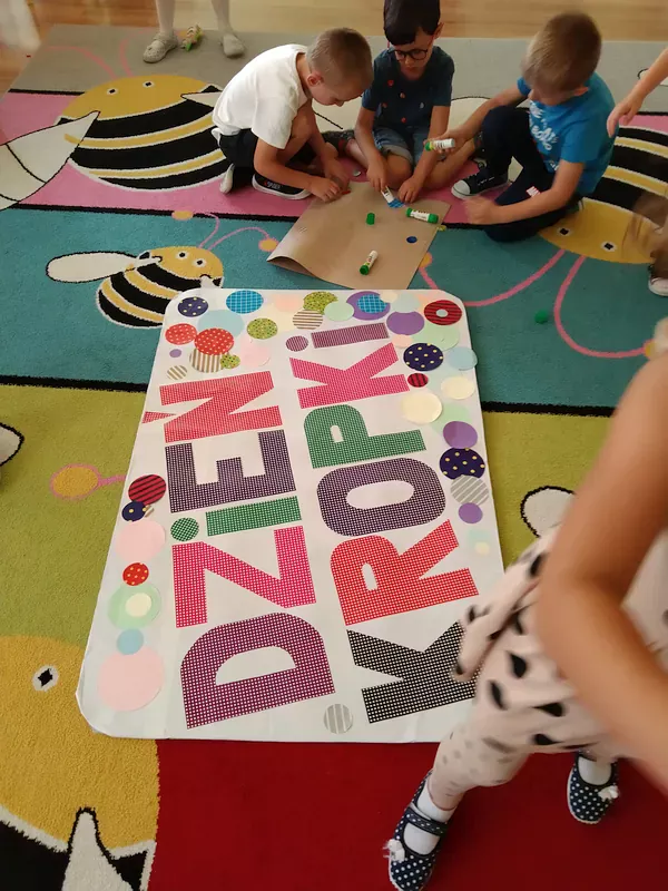 Dzieci podczas ozdabiania plakatu z napisem.