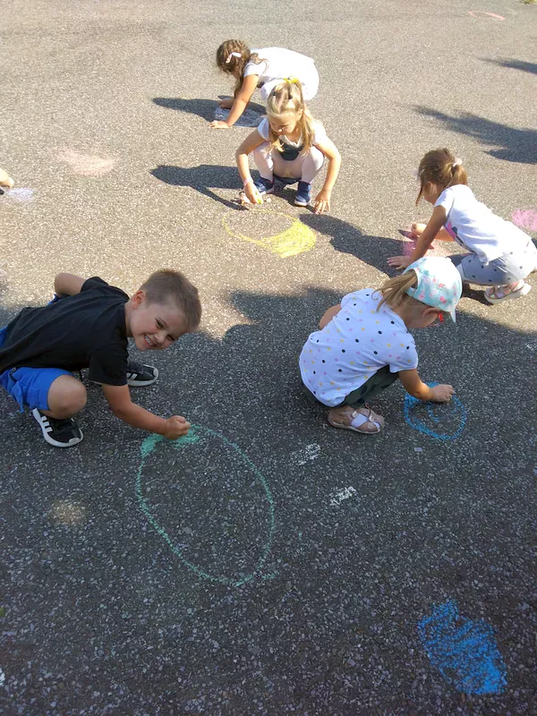 Dzieci malujące kropkę kredą na betonie.