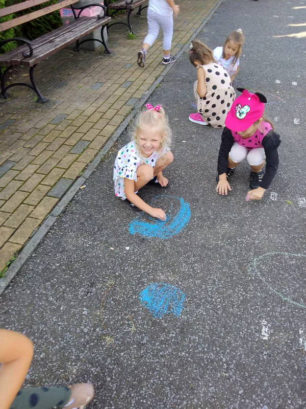 . Dzieci malujące kropkę kredą na betonie.