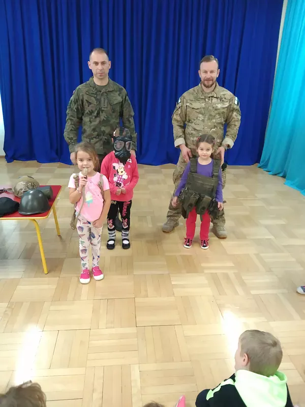 Dzieci przymierzają żołnierskie sprzęty.