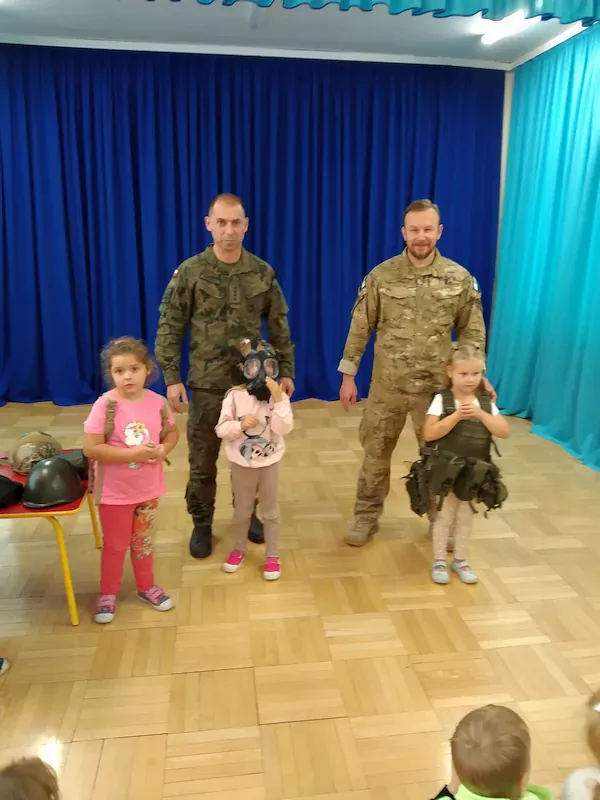Dzieci przymierzają żołnierskie sprzęty.