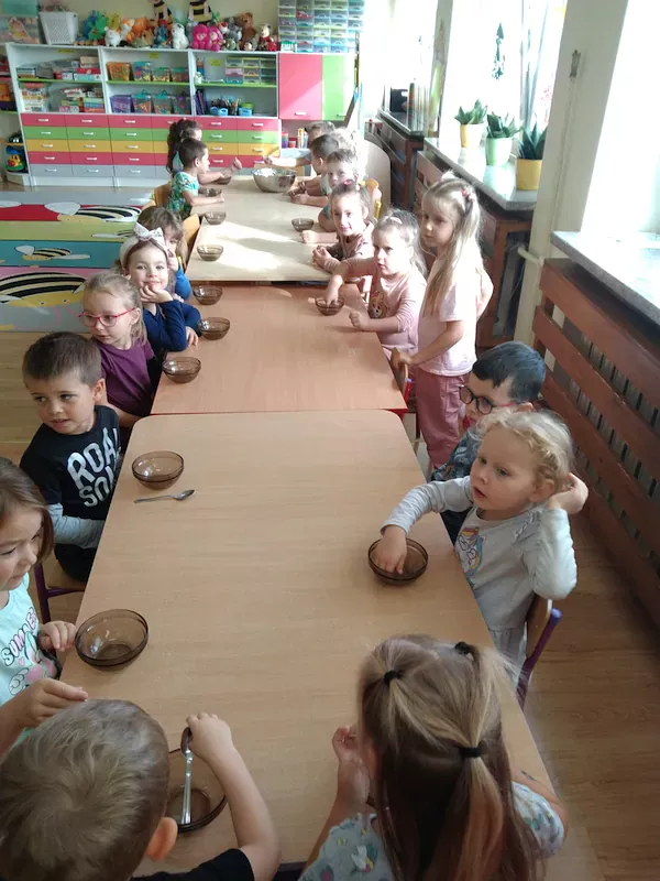 Dzieci przy stoliku z miseczkami na sałatkę owocową