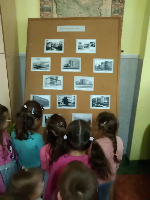 Dzieci przed tablicą ze zdjęciami naszego miasta z dawnych czasów