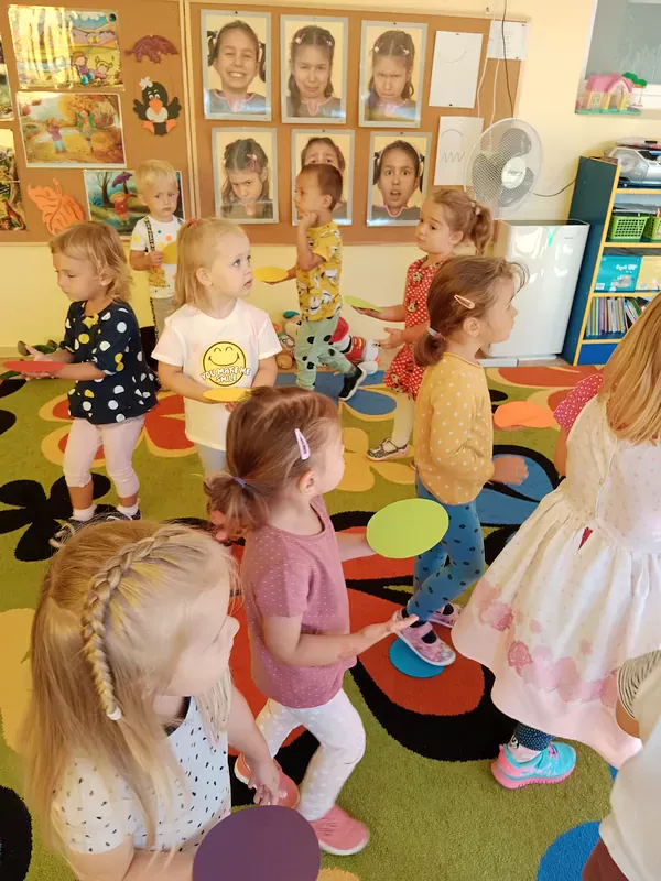 Zabawy dzieci z kolorowymi kropeczkami – na polecenie nauczyciela kładą na ręce