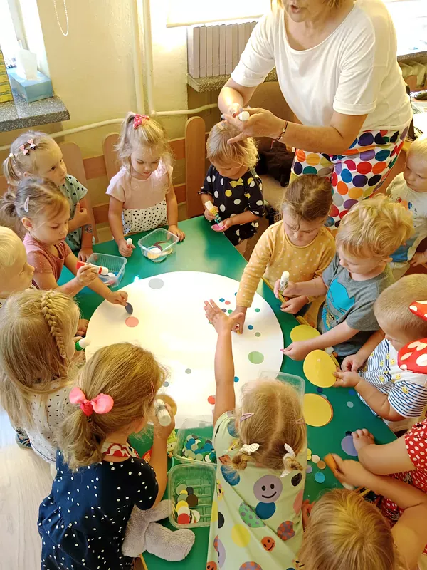 Dzieci wyklejają kropkę XXL z białego brystolu kolorowymi kropeczkami