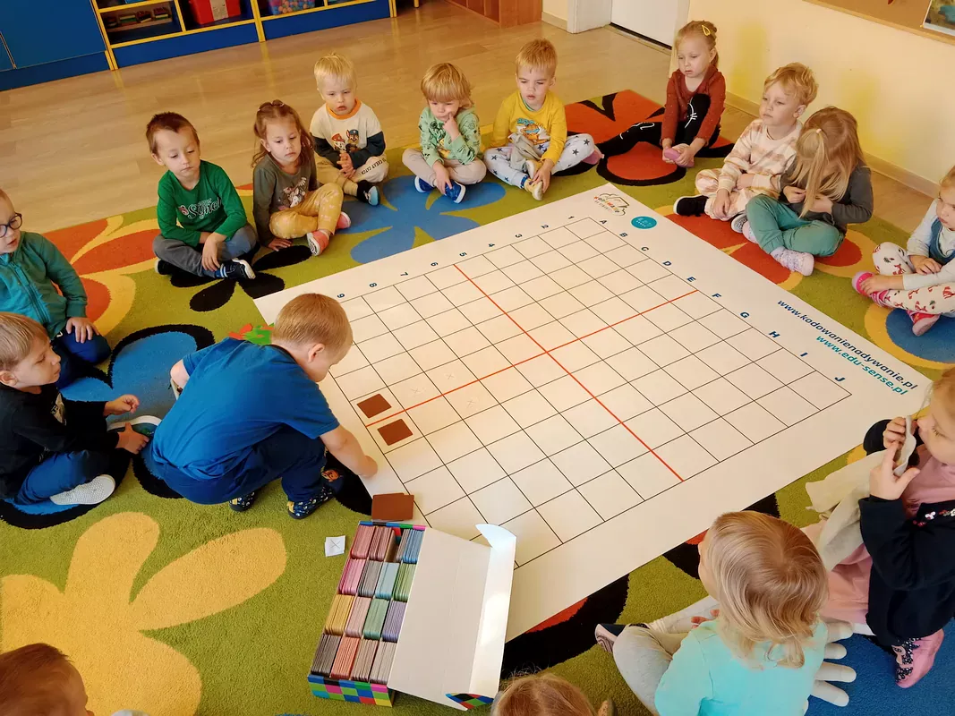 Hubert układa kolorowe kartoniki według instrukcji czytanej przez nauczyciela