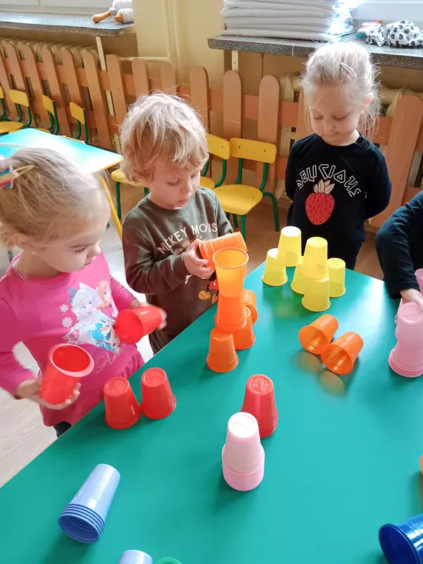 Dzieci układają wieże z kolorowych kubeczków