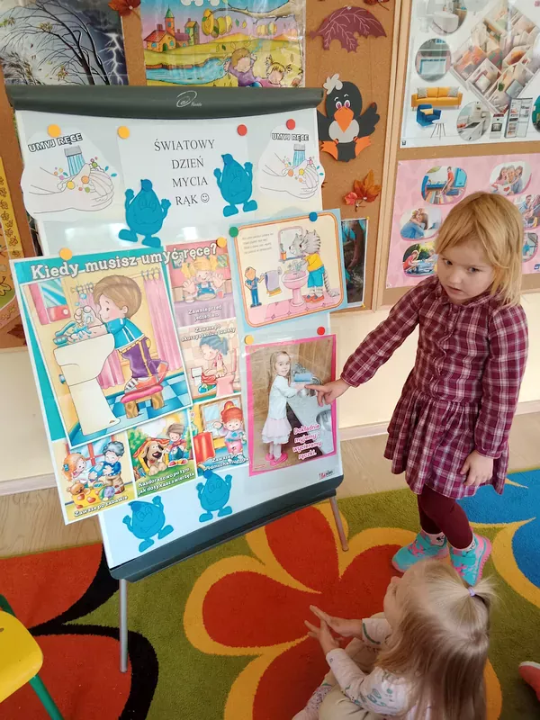 Emma wskazuje ilustrację przedstawiającą dziewczynkę myjącą ręce