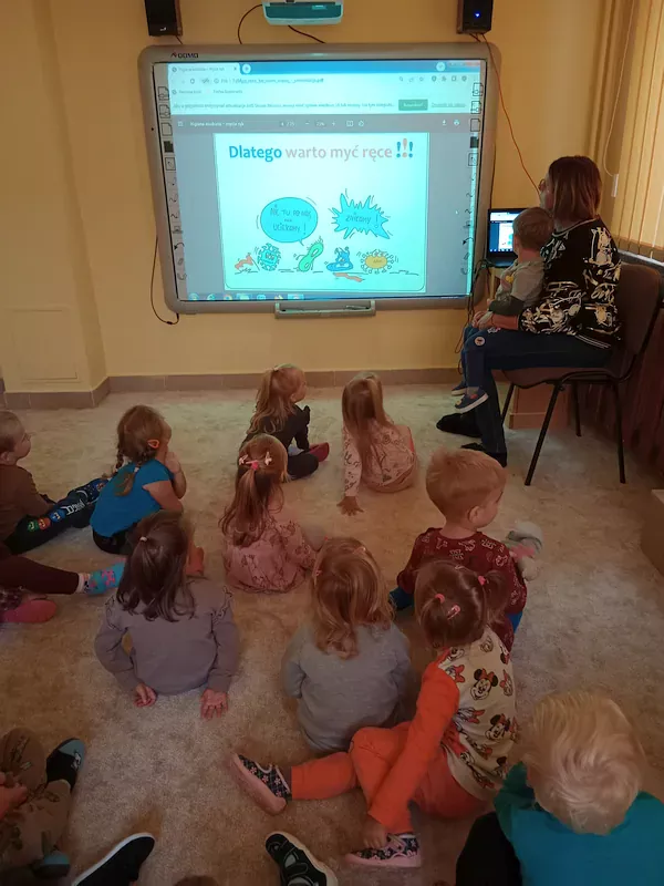 Dzieci oglądają prezentację multimedialną Państwowej Inspekcji Sanitarnej „Myję ręce, bo wiem więcej”