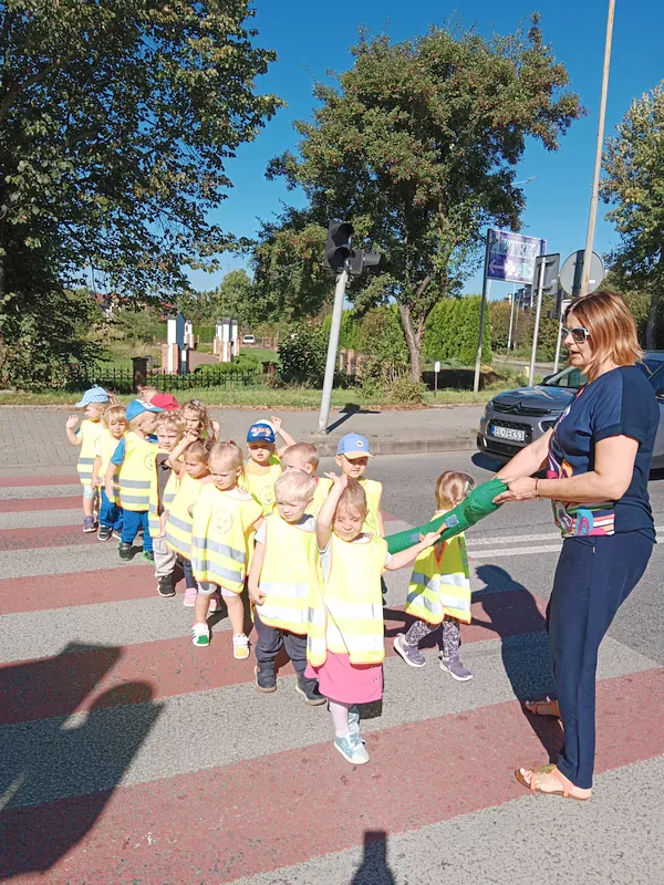 Dzieci przechodzą przez przejście dla pieszych z sygnalizacją świetlną